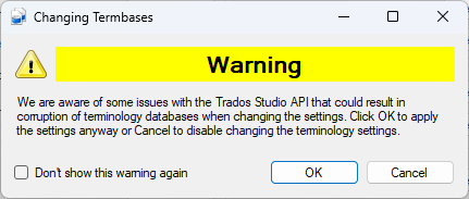 Screenshot of a warning dialog titled 'Changing Termbases' with a yellow warning icon. Text reads: 'We are aware of some issues with the Trados Studio API that could result in corruption of terminology databases when changing the settings. Click OK to apply the settings anyway or Cancel to disable changing the terminology settings.' Options include 'Don't show this warning again' checkbox, 'OK', and 'Cancel' buttons.