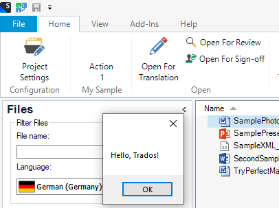 Trados Studio screenshot showing a custom ribbon group labeled 'My Sample' with an 'Action 1' button. A message box with 'Hello, Trados!' is displayed over the Files view, indicating the action button works as expected.