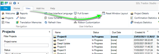 Trados Studio interface showing the 'Welcome' screen with a list of projects. A green arrow points to the 'Reset Window Layout' button in the toolbar.